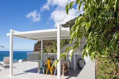 a white pergola with chairs and tables on a patio at Villa Nicuma by ESCAPE to Madeira in Calheta
