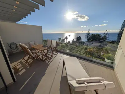 a balcony with a table and chairs and a view of the ocean at Breathtaking Oceanfront Living, Sunset Facing 3-Bedroom Flat in Acqua Residences in Funchal