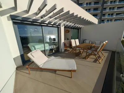 a patio with a table and chairs on a balcony at Breathtaking Oceanfront Living, Sunset Facing 3-Bedroom Flat in Acqua Residences in Funchal