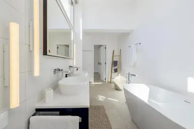 a white bathroom with a tub and a sink at Vila Golfinho, with heated pool, rooftop lounge and ocean views in Luz