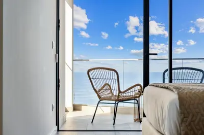 a bedroom with a bed and two chairs on a balcony at Atlantis Apartment in Câmara de Lobos