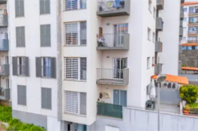 a tall white building with windows and balconies at Sapphire Scape Assomada Madeira by GRM in Bicas