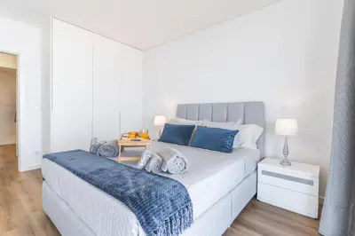a white bedroom with a large bed with blue pillows at Atlantic View Apartment by Atlantic Holiday in Câmara de Lobos