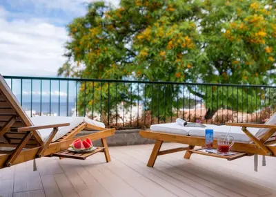 a balcony with a bed and chairs on a deck at Madeira Precious Family Apartment in Funchal