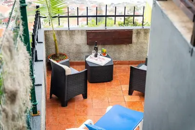 a patio with a table and chairs and a plant at Whale's Lodge in Porto Moniz