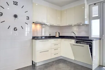 a kitchen with white cabinets and a clock on the wall at Baia Cliff View, a Home in Madeira in Funchal