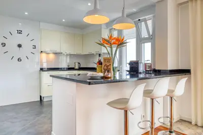 a kitchen with a counter with stools and a clock at Baia Cliff View, a Home in Madeira in Funchal