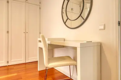 a white desk with a chair and a clock on the wall at Baia Cliff View, a Home in Madeira in Funchal