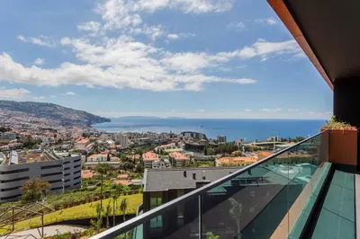a balcony with a view of the city and the ocean at Horizon Funchal in Funchal