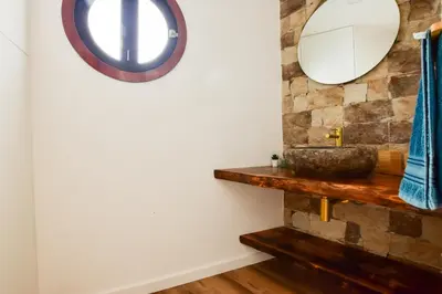 a bathroom with a stone wall and a mirror at A Casa da Graça Reis by Horizon View Madeira in São Vicente