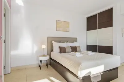 a white bedroom with a large bed and a table at Forum Garden View 5A by Homie in Funchal