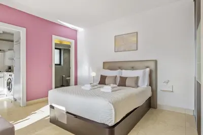 a bedroom with a large bed and a pink wall at Forum Garden View 5A by Homie in Funchal