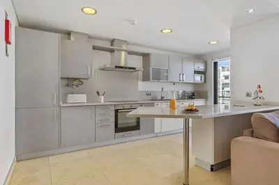 a kitchen with stainless steel appliances and a table at Forum Ocean View 5C by Homie in Funchal