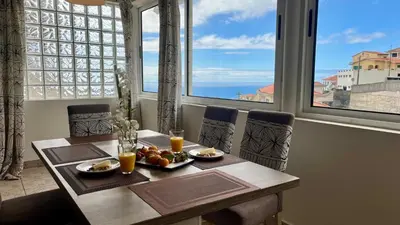a table with a bowl of fruit and two glasses of orange juice at ZainAli Guest House in Funchal