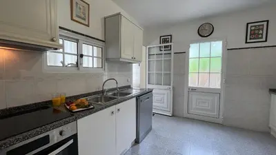 a kitchen with white cabinets and a sink and a window at ZainAli Guest House in Funchal