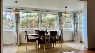 a dining room with a table and a large window at ZainAli Guest House in Funchal