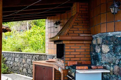 an outdoor kitchen with a brick oven in a house at Refúgio do Norte in Porto Moniz
