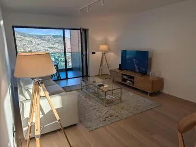 a living room with a couch and a tv at Sky-High Elegance Top-Floor Views of City, Ocean & Sunrise in Funchal