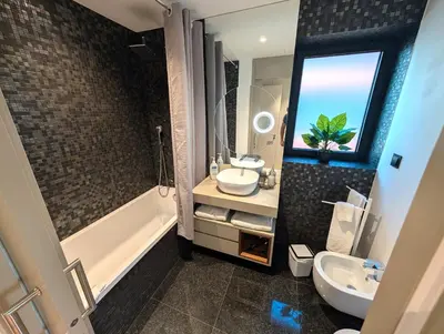 a bathroom with a sink and a tub and a mirror at Sky-High Elegance Top-Floor Views of City, Ocean & Sunrise in Funchal