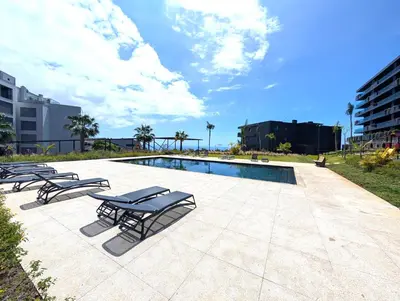 a swimming pool with lounge chairs next to a building at Sky-High Elegance Top-Floor Views of City, Ocean & Sunrise in Funchal