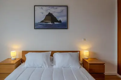 a bedroom with a bed with two night stands and two lamps at Garajau Sea View in Caniço