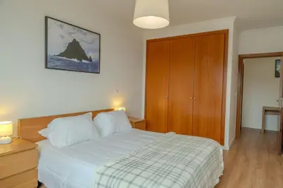a bedroom with a bed and a wooden cabinet at Garajau Sea View in Caniço