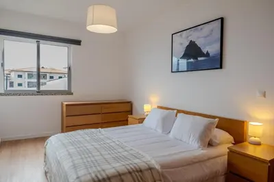 a bedroom with a bed and two lamps and a window at Garajau Sea View in Caniço