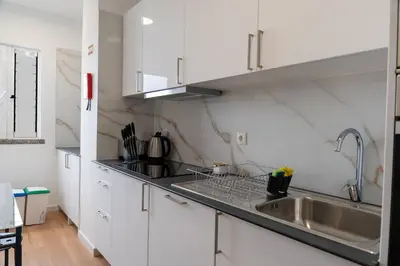 a kitchen with white cabinets and a stainless steel sink at Garajau Sea View in Caniço