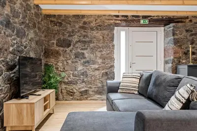 a living room with a couch and a stone wall at Villa Pomar, By OP in Senhora do Rosário