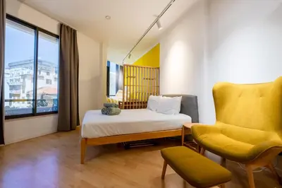 a bedroom with a bed and a yellow chair at Yellow Sun Studio - Cozy Stay in Central Funchal in Funchal