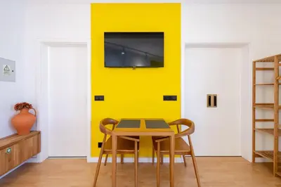 a yellow wall in a room with a table and chairs at Yellow Sun Studio - Cozy Stay in Central Funchal in Funchal
