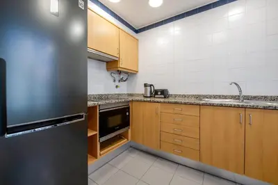 a kitchen with wooden cabinets and a stainless steel refrigerator at Yellow Sun Studio - Cozy Stay in Central Funchal in Funchal