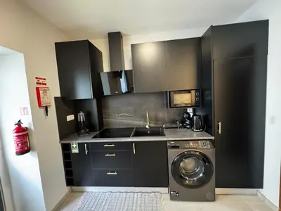 a kitchen with black cabinets and a washing machine at São Pedro Paradise B Down in Funchal