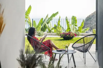 a woman sitting in a chair on a patio at Villa Wiktoria, by Pausa Holiday Rentals in Ribeira Brava