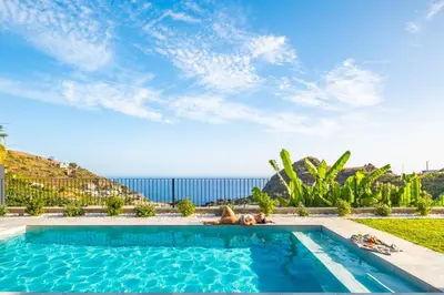 a woman laying in a pool with the ocean in the background at Villa Wiktoria, by Pausa Holiday Rentals in Ribeira Brava