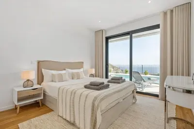 a white bedroom with a bed and a balcony at Villa Wiktoria, by Pausa Holiday Rentals in Ribeira Brava