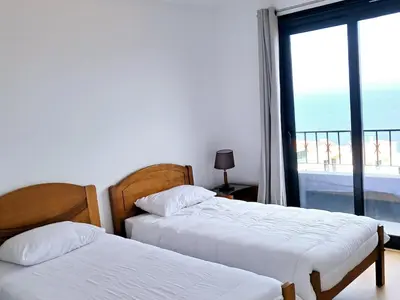 two beds in a room with a view of the ocean at House Virginia in Santa Cruz