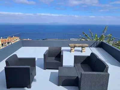 a patio with two chairs and a table and the ocean at House Virginia in Santa Cruz