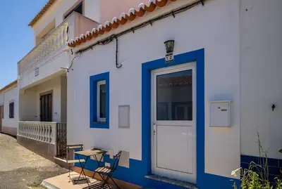 a blue and white building with a door and a table at Cantinho da Deolinda in Luz