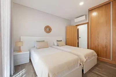 a white bedroom with two beds and a clock on the wall at Casa das Raposinhas V, Funchal in Funchal