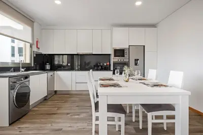 a white kitchen with a white table and chairs at Casa das Raposinhas V, Funchal in Funchal
