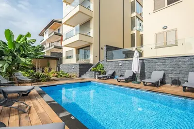 a swimming pool with chairs and a building at Casa das Raposinhas V, Funchal in Funchal