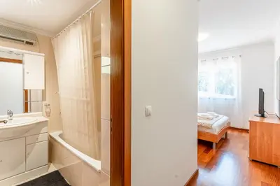 a bathroom with a sink and a bed in a room at Bright Modern 2BR Apartment Near Cristo Rei in Caniço
