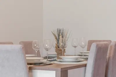 a dining room table with glasses and plates on it at Bright Modern 2BR Apartment Near Cristo Rei in Caniço