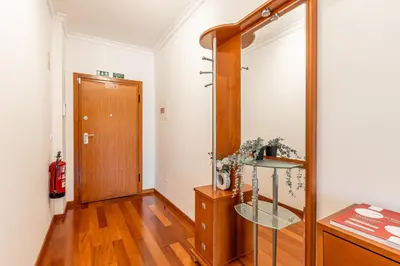 a hallway with a wooden door and a wooden floor at Bright Modern 2BR Apartment Near Cristo Rei in Caniço