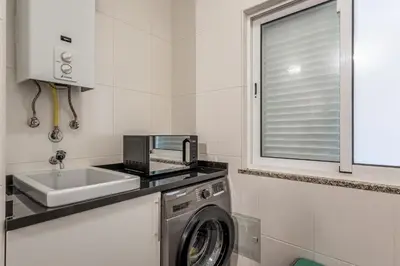 a kitchen with a washing machine and a sink at Bright Modern 2BR Apartment Near Cristo Rei in Caniço