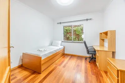 a room with a bed and a desk and a window at Ti Clara in Caniço