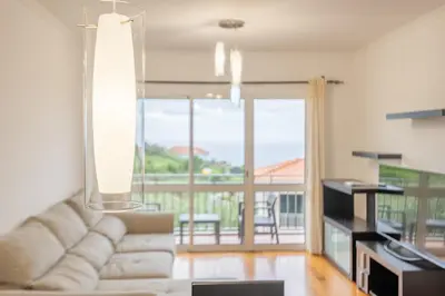 a living room with a white couch and a balcony at Ti Clara in Caniço