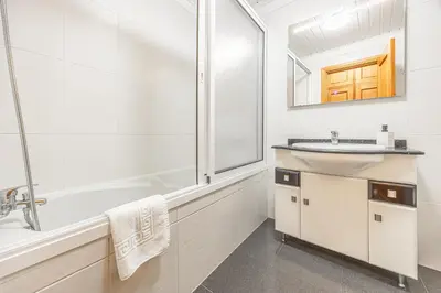 a white bathroom with a sink and a shower at Ti Clara in Caniço