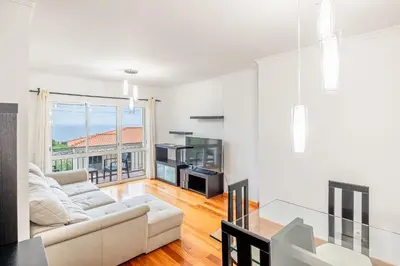 a living room with a white couch and a glass table at Ti Clara in Caniço